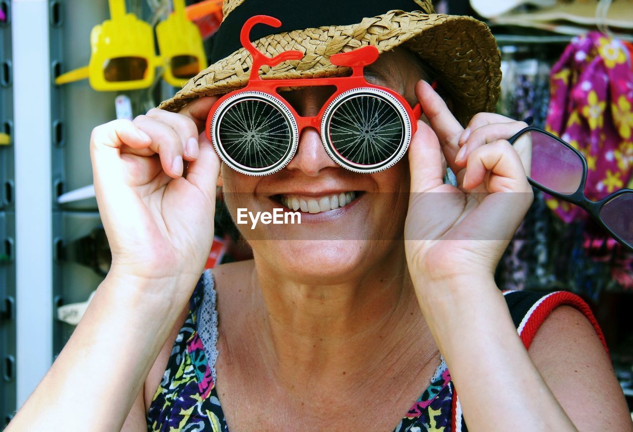 Mid adult woman looking through funky sunglasses