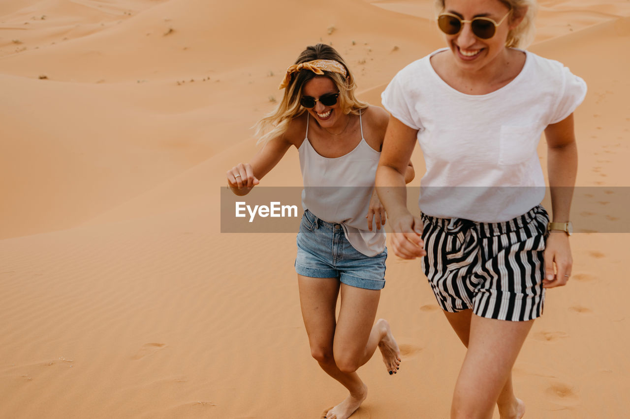 Cheerful young friends running at desert