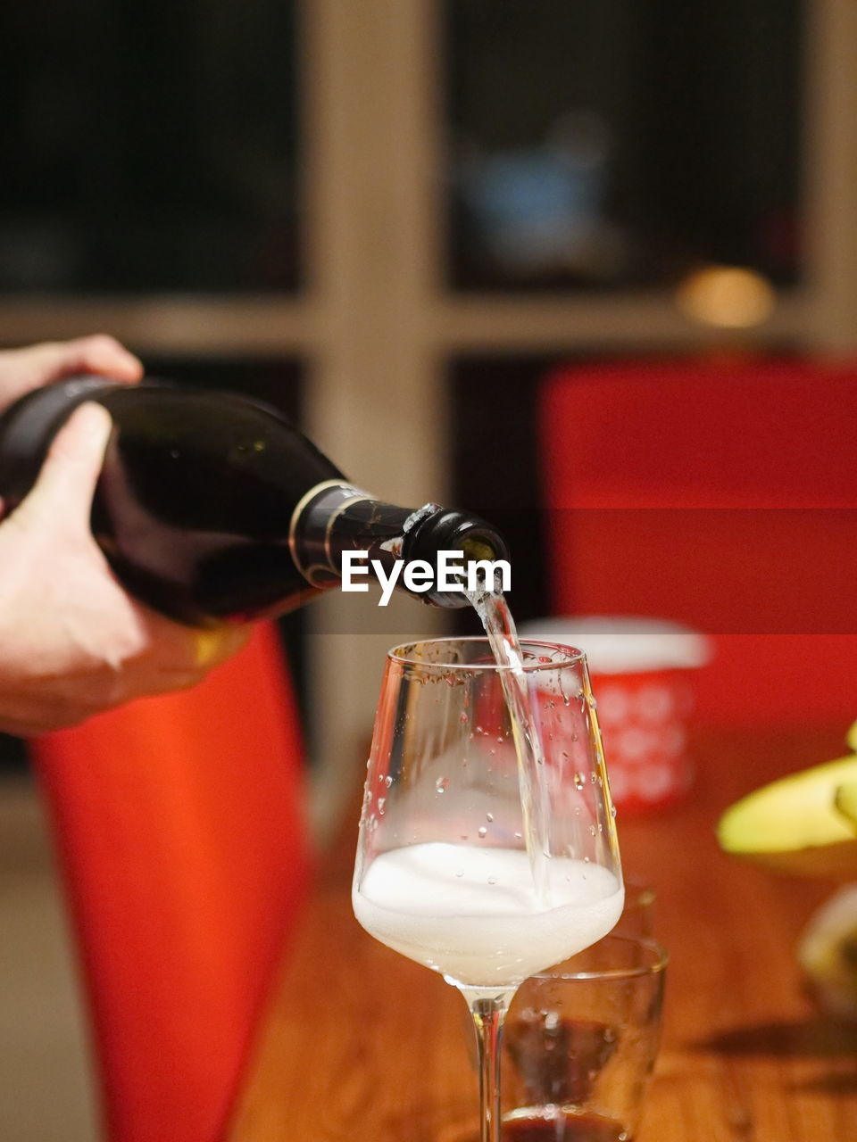 Cropped image of hands pouring wine in glass on table