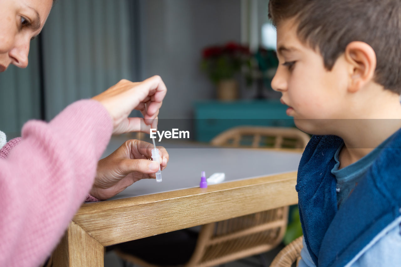 Mother doing an antigen test to her son at home