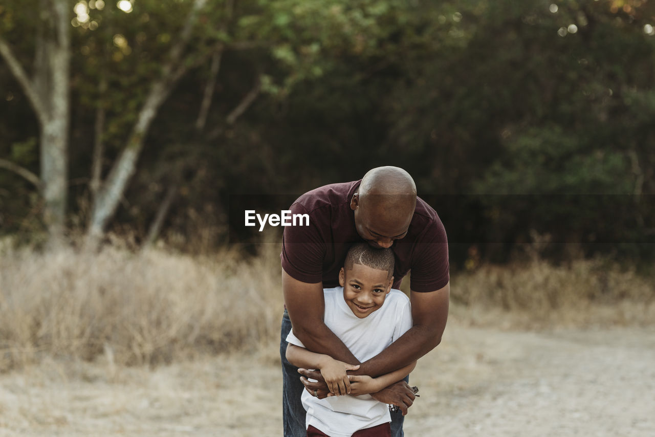 Close up of happy father and son hugging in backlit field