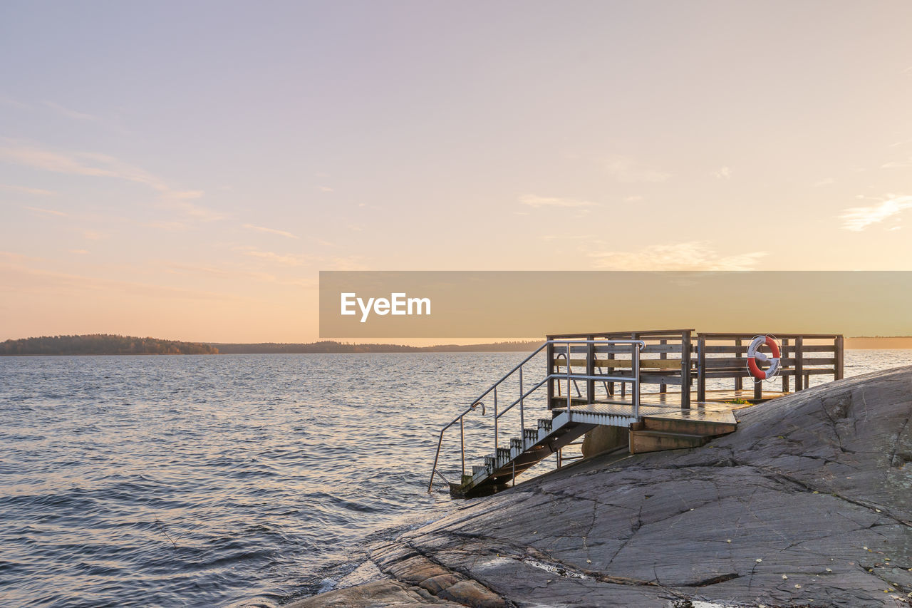 Viewing deck with stairs to baltic sea in stockholm stunning sunrise with rocks in beautiful light