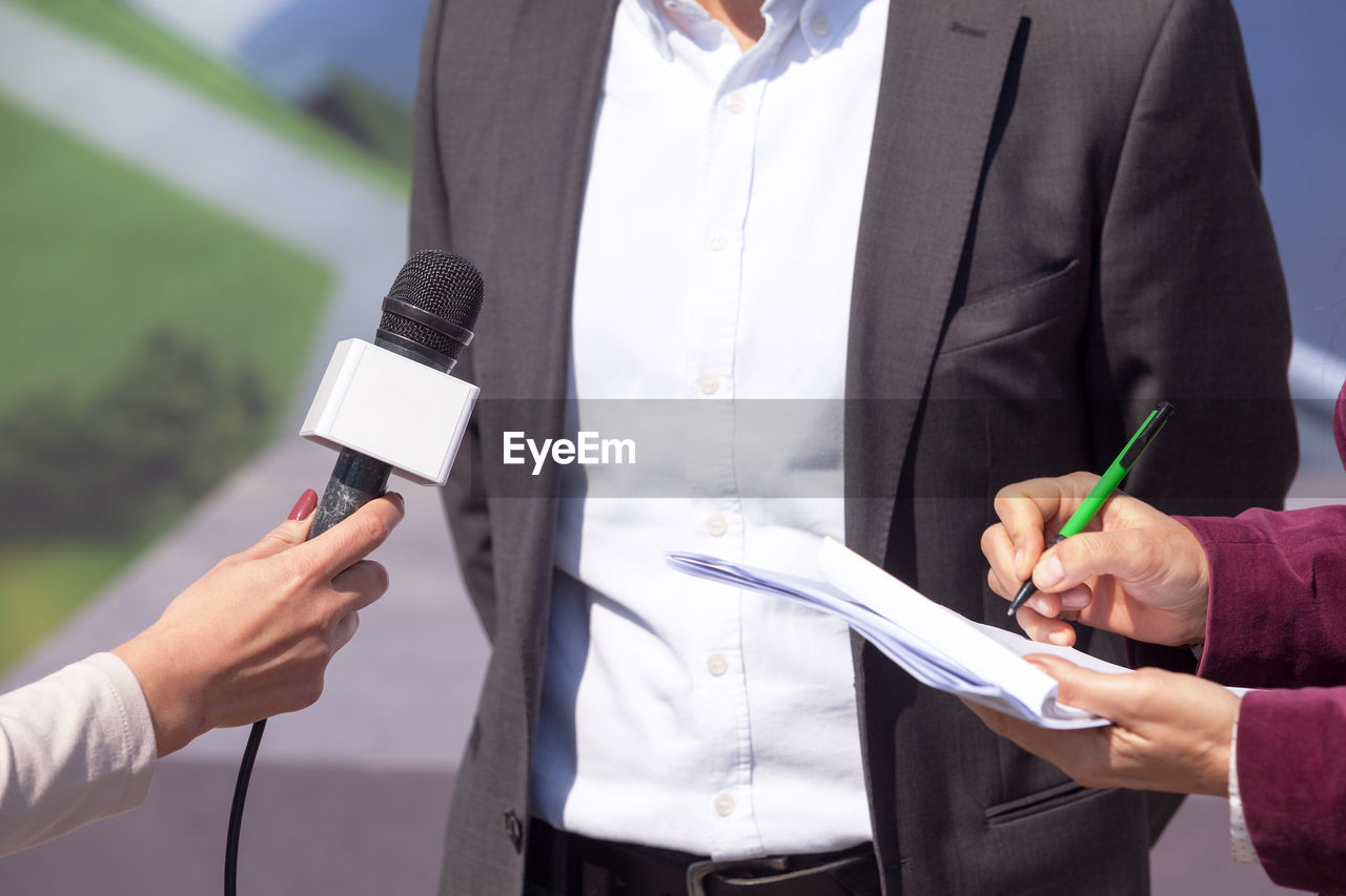 Cropped image of journalists interviewing businessman