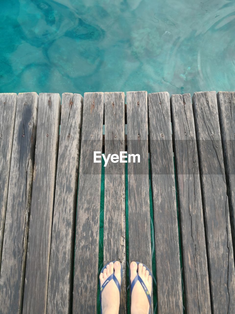 Low section of woman on boardwalk by swimming pool