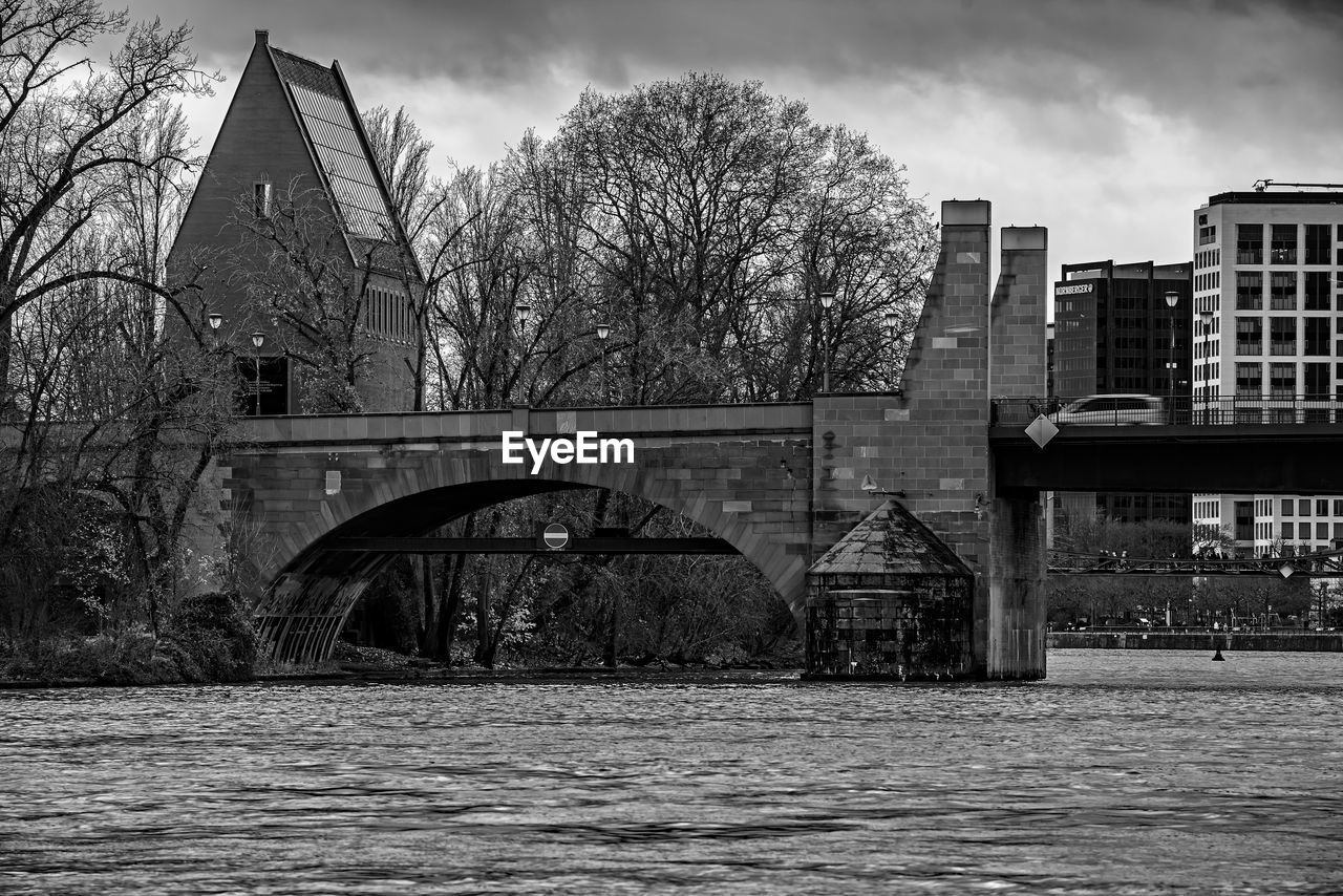 architecture, built structure, black and white, building exterior, monochrome, monochrome photography, tree, sky, bridge, nature, building, city, water, urban area, bare tree, cloud, plant, river, no people, cityscape, darkness, black, winter, outdoors, house, transportation, day