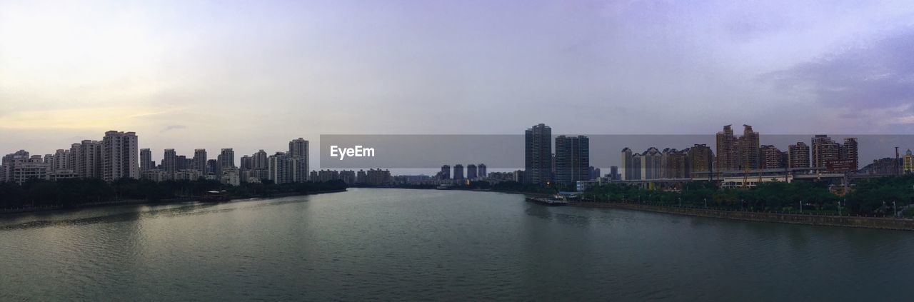 Panoramic view of river by city against sky