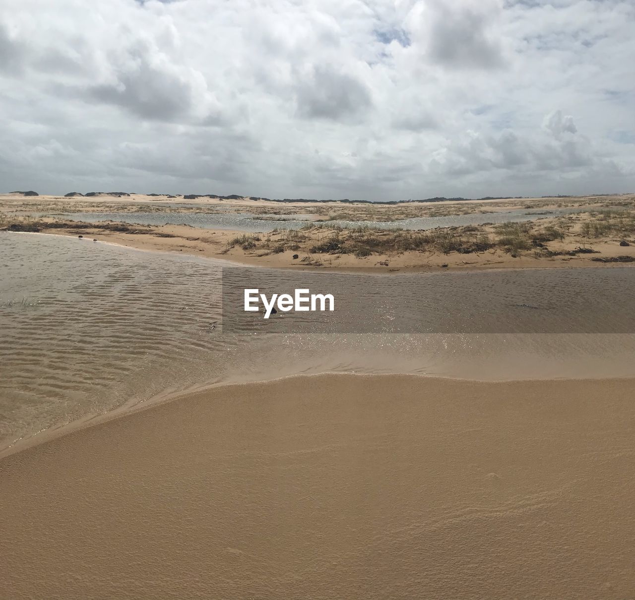 SCENIC VIEW OF BEACH AGAINST CLOUDY SKY