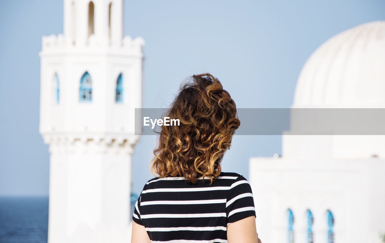 Rear view of a woman against cropped built structure