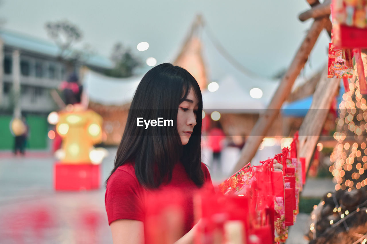 Young woman looking away while standing outdoors