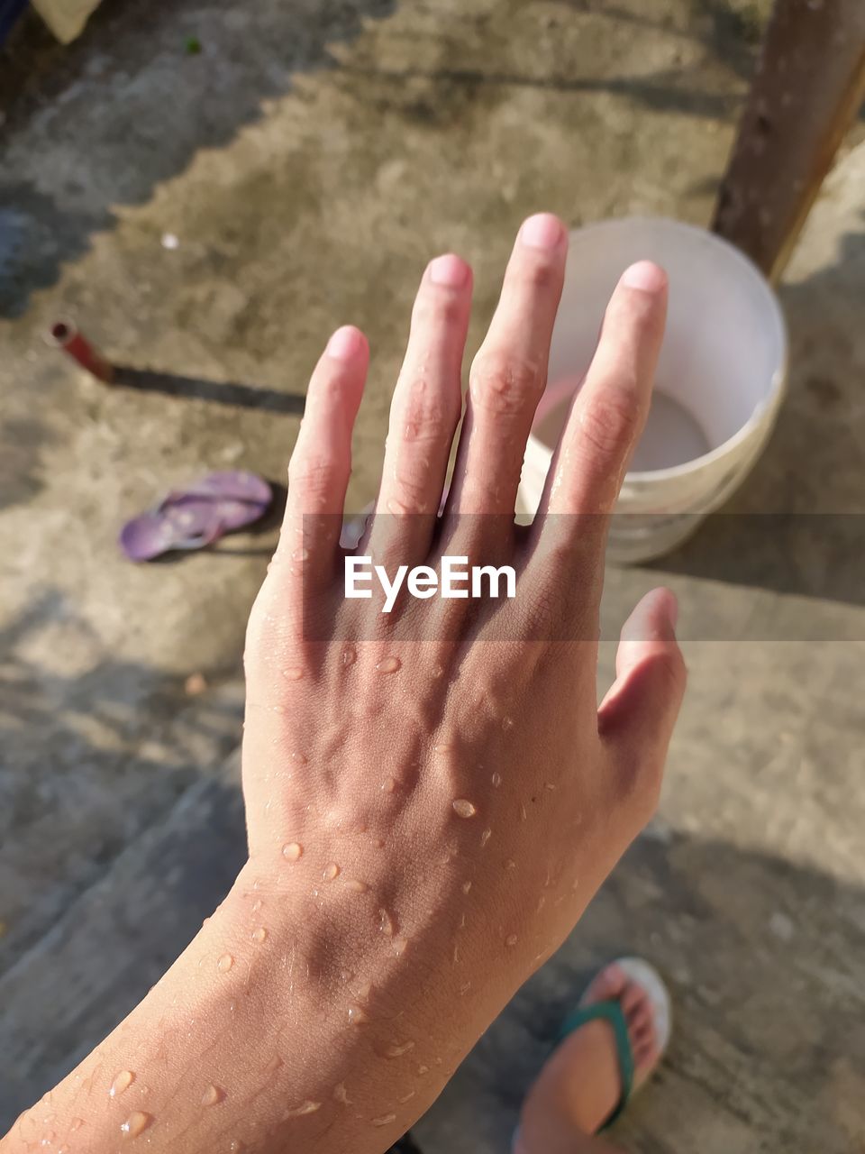 HIGH ANGLE VIEW OF WOMAN HAND ON WET WALL