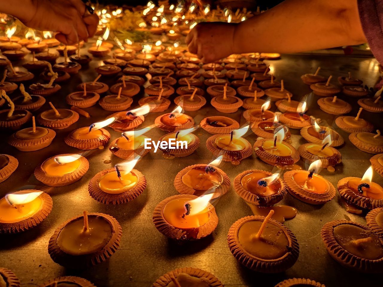 Cropped hands of people burning tea lights