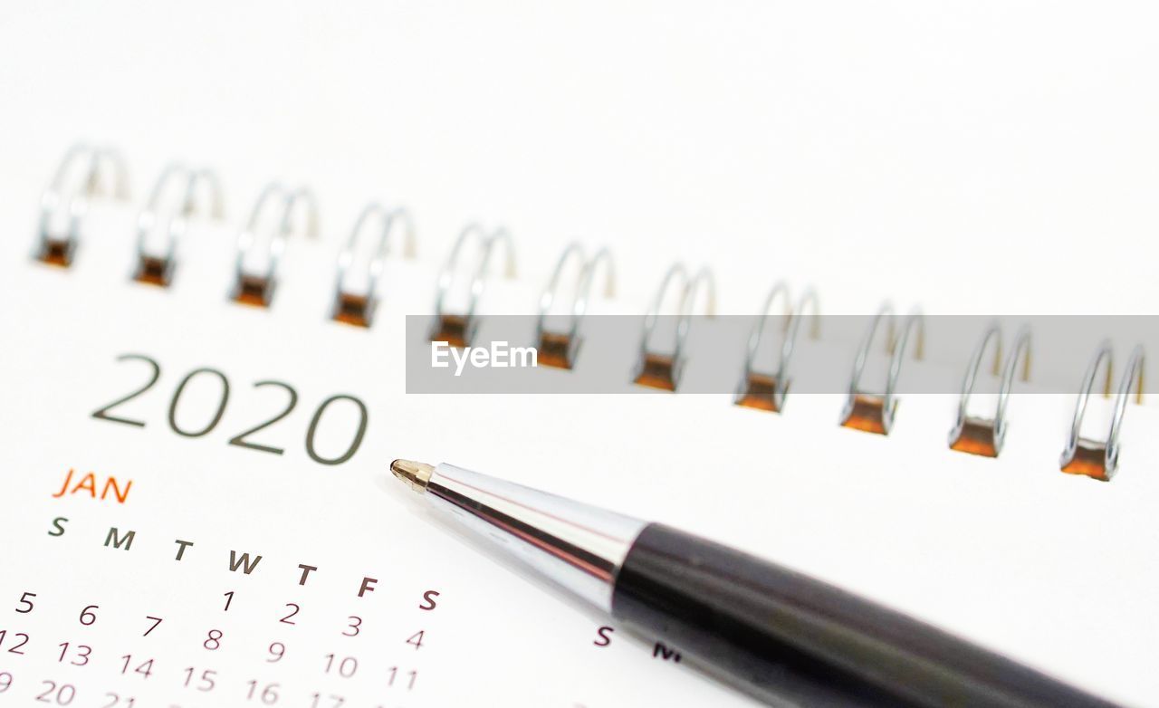 Close-up of pen on calendar against white background