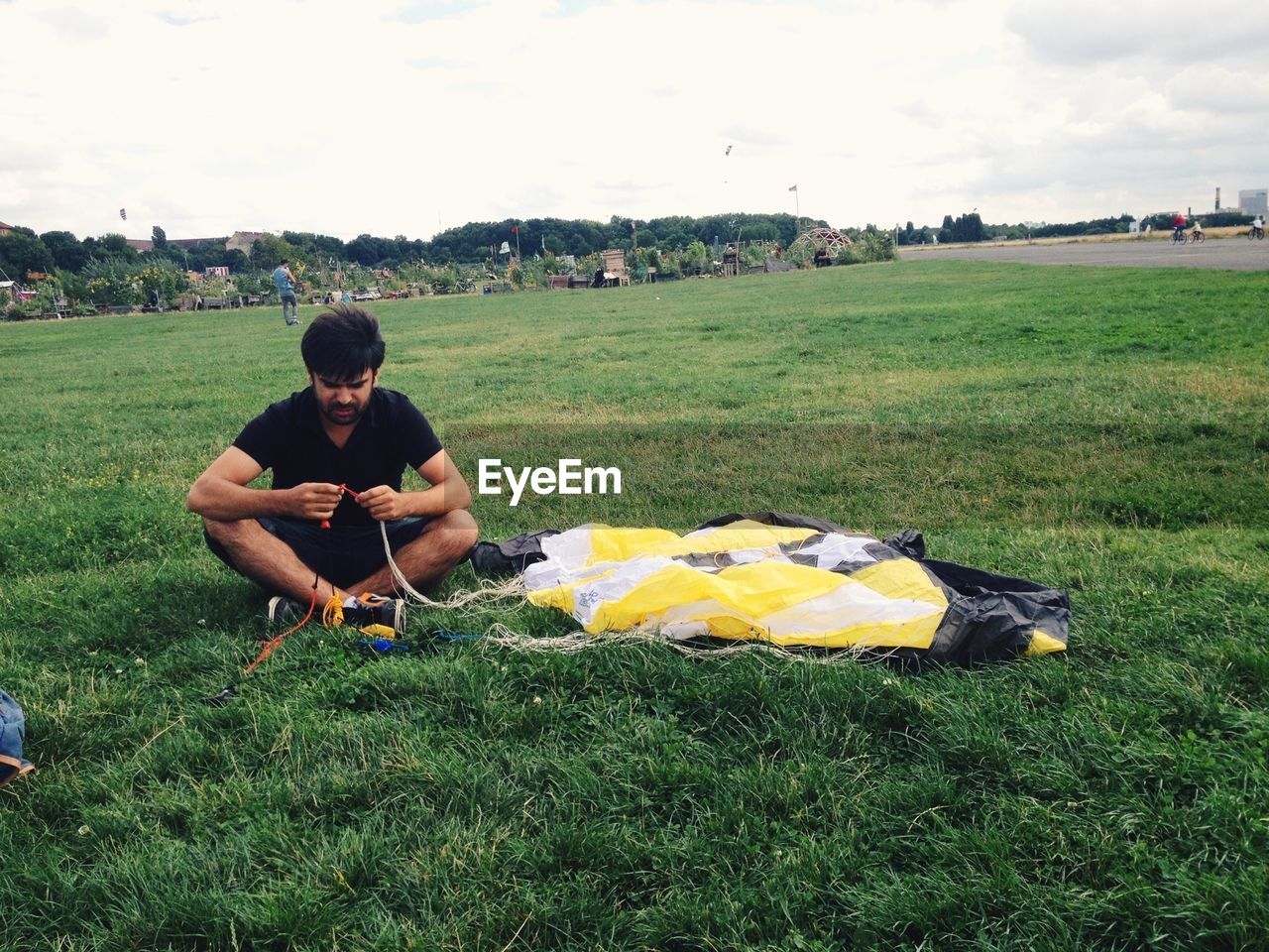 A young man prepares a parachute in an open field