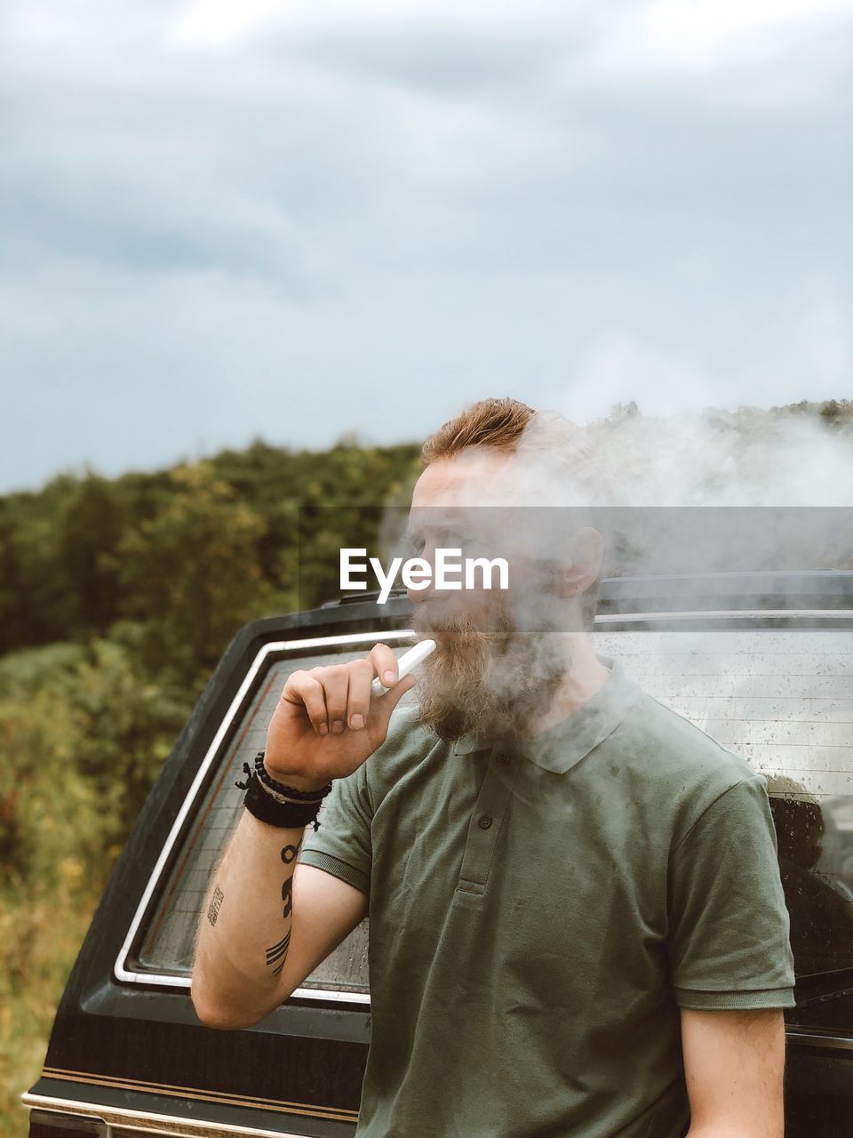 Full length of man holding electric cigarette against sky