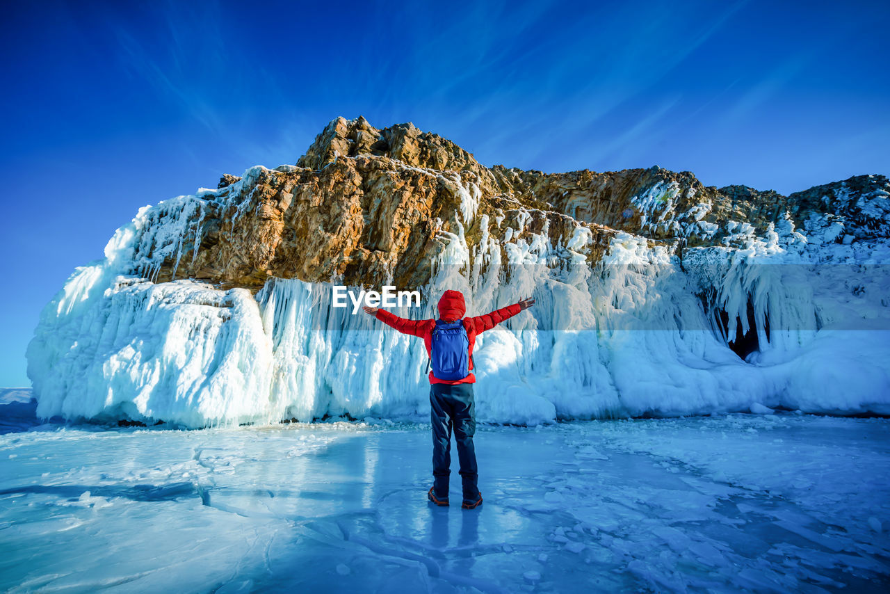 MAN STANDING ON SNOW AGAINST BLUE SKY