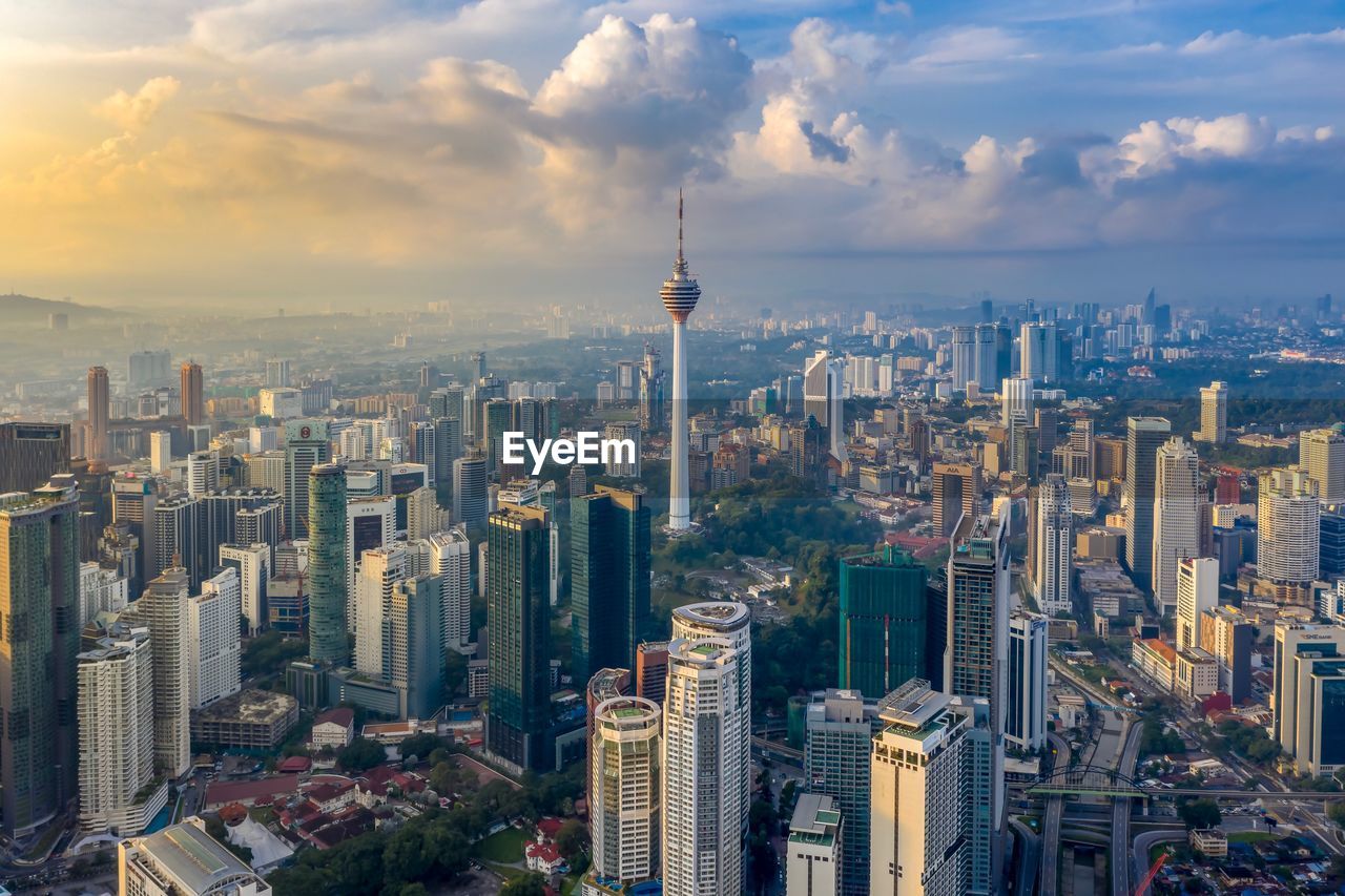 Aerial view of buildings in city against cloudy sky