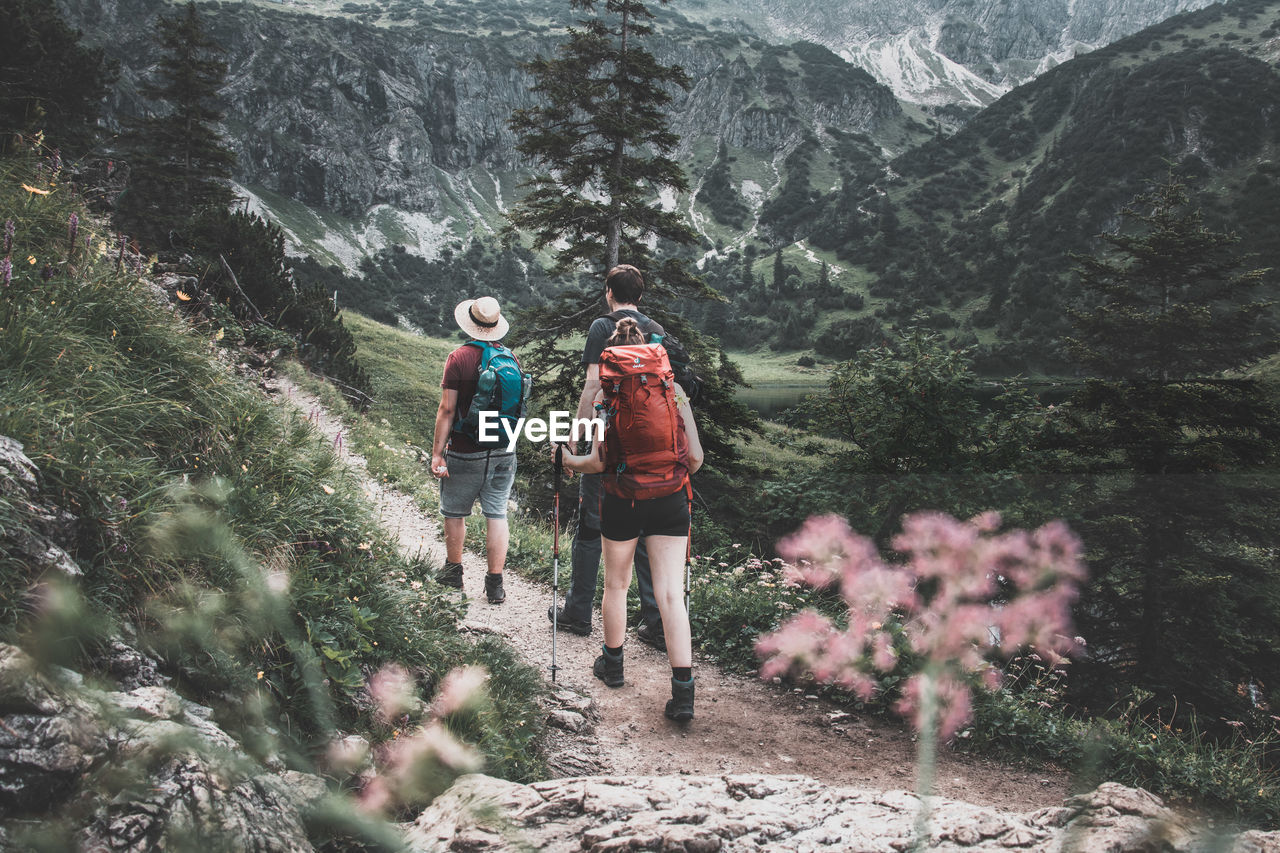 REAR VIEW OF WOMAN WALKING ON MOUNTAIN