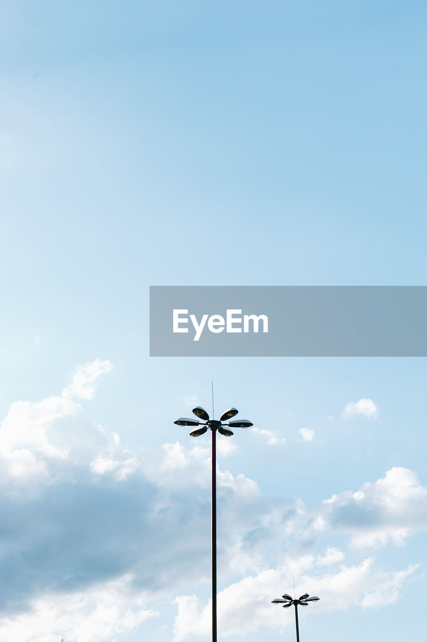 Low angle view of street lights against cloudy sky