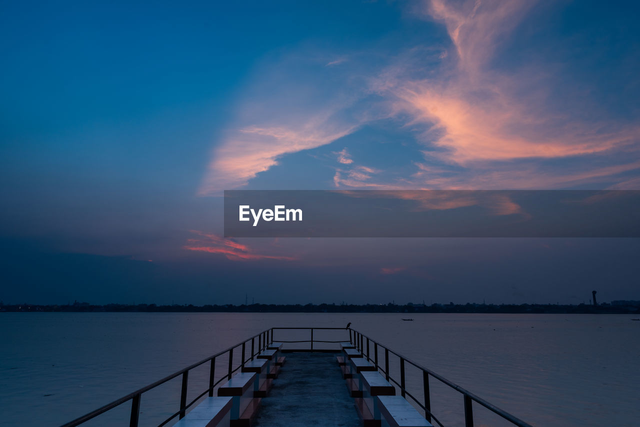 Pier over sea against sky during sunset