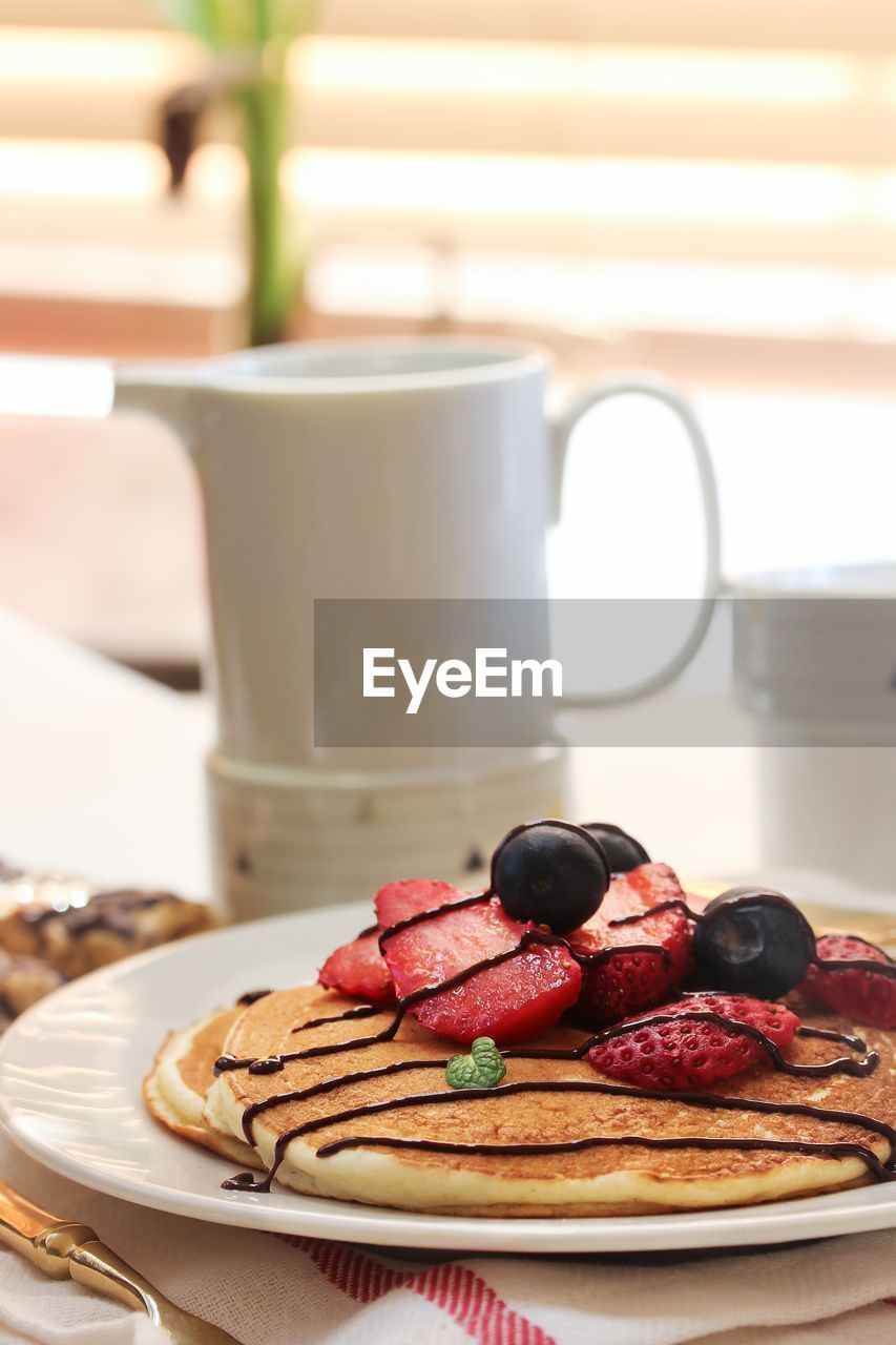 Close-up of fruits on pancake in plate at table