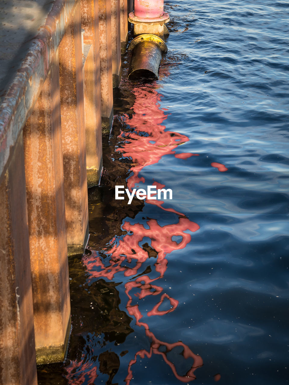 Reflection of pink water pipe in river