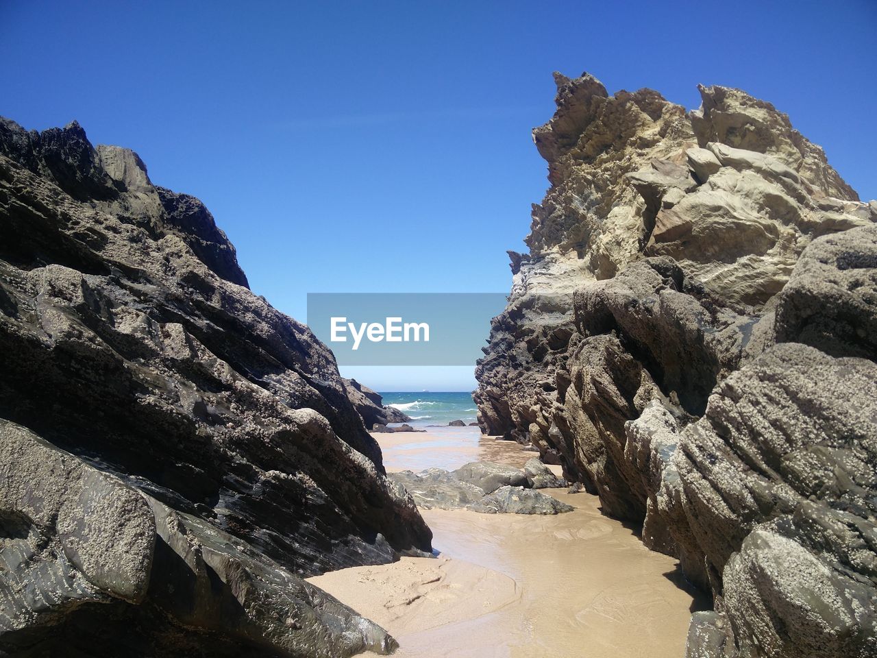 ROCK FORMATION AT BEACH AGAINST CLEAR SKY
