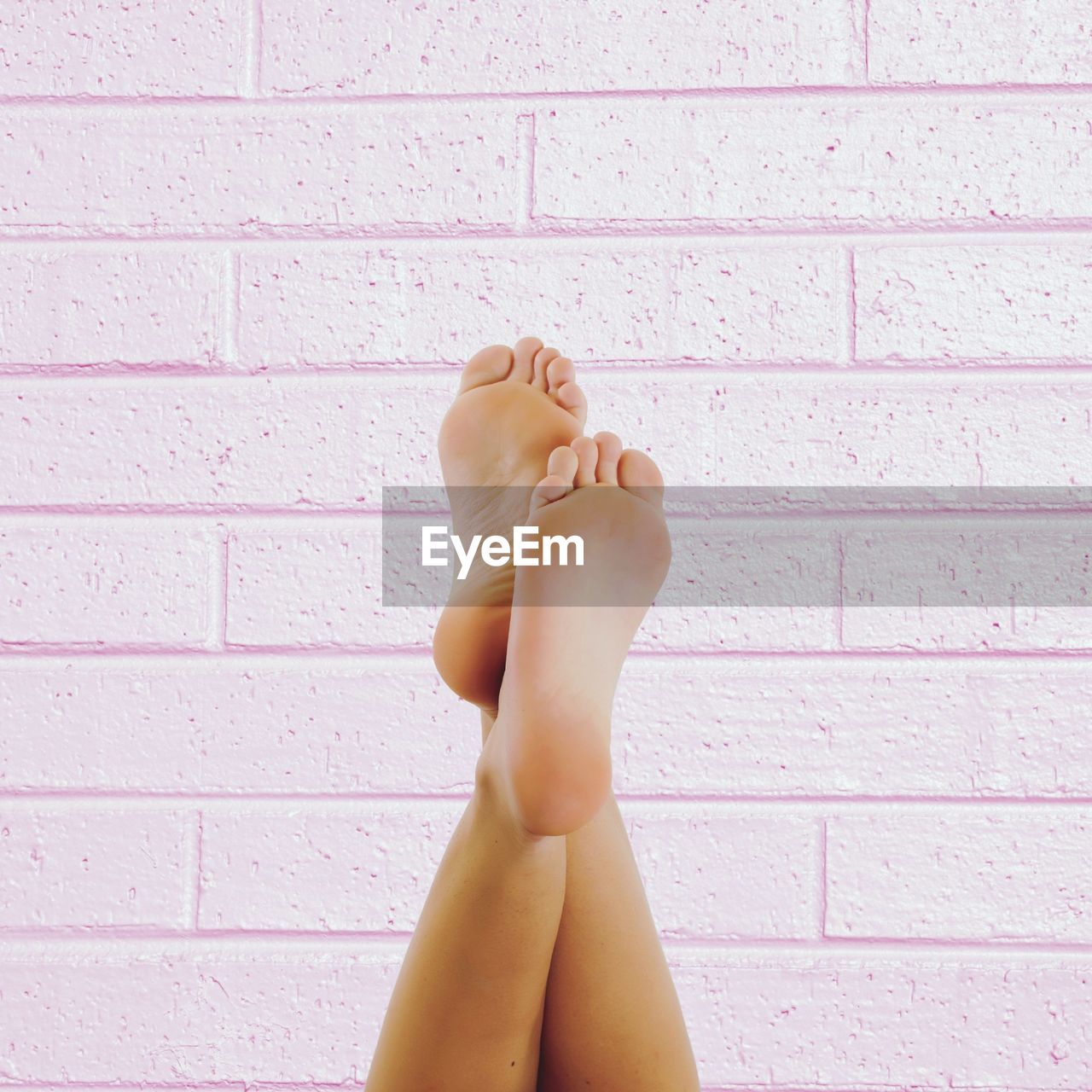 Low section of naked woman standing against wall