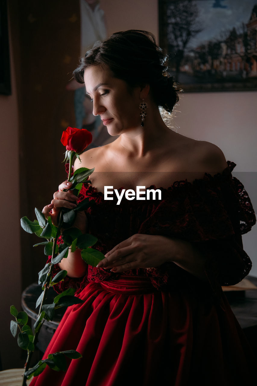 Beautiful woman in vintage 1800s early 1900s clothing red dress in old interior. historical dresses