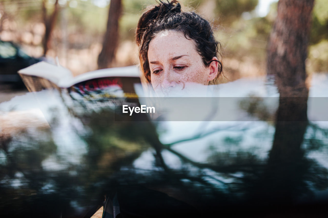 Portrait of woman with reflection of trees in water