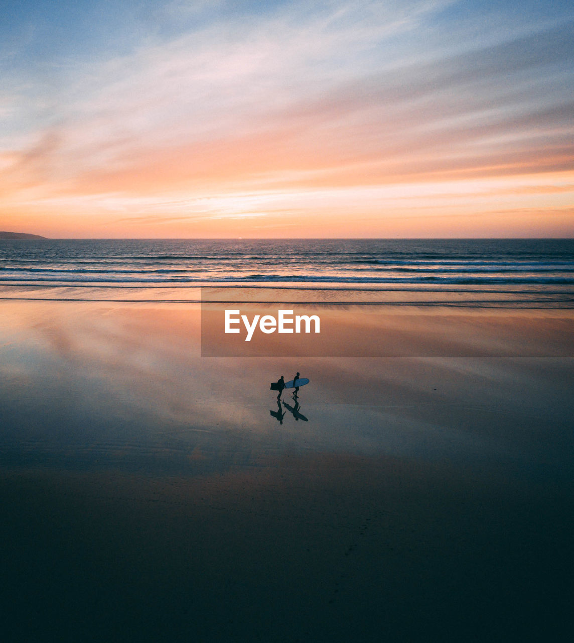 High angle view of people walking at beach against sky during sunset