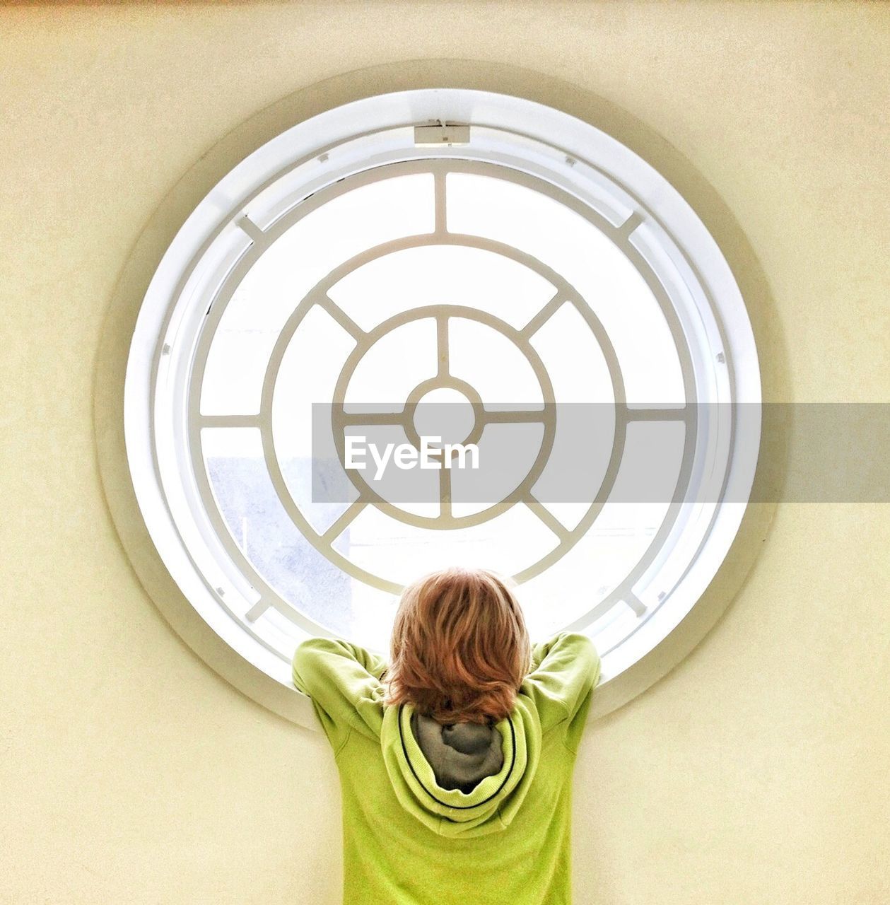 Rear view of boy looking through window