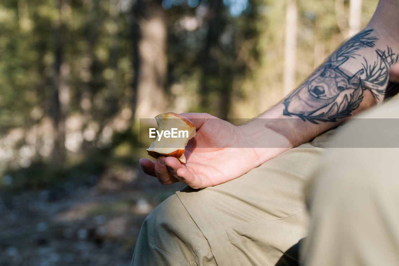 Close-up of inked male arm holding an apple