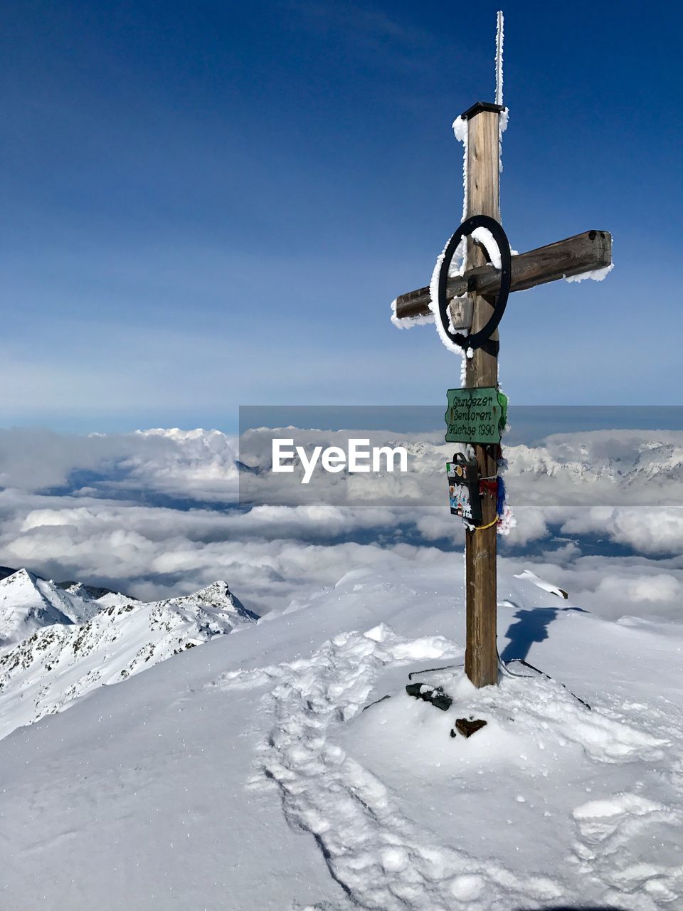 Cross on snow covered field against sky