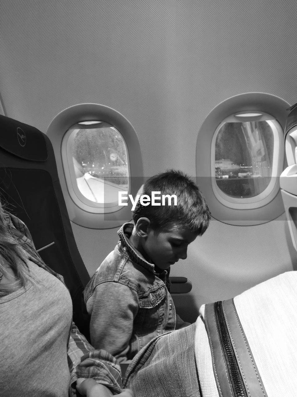 Side view of boy sitting by airplane window