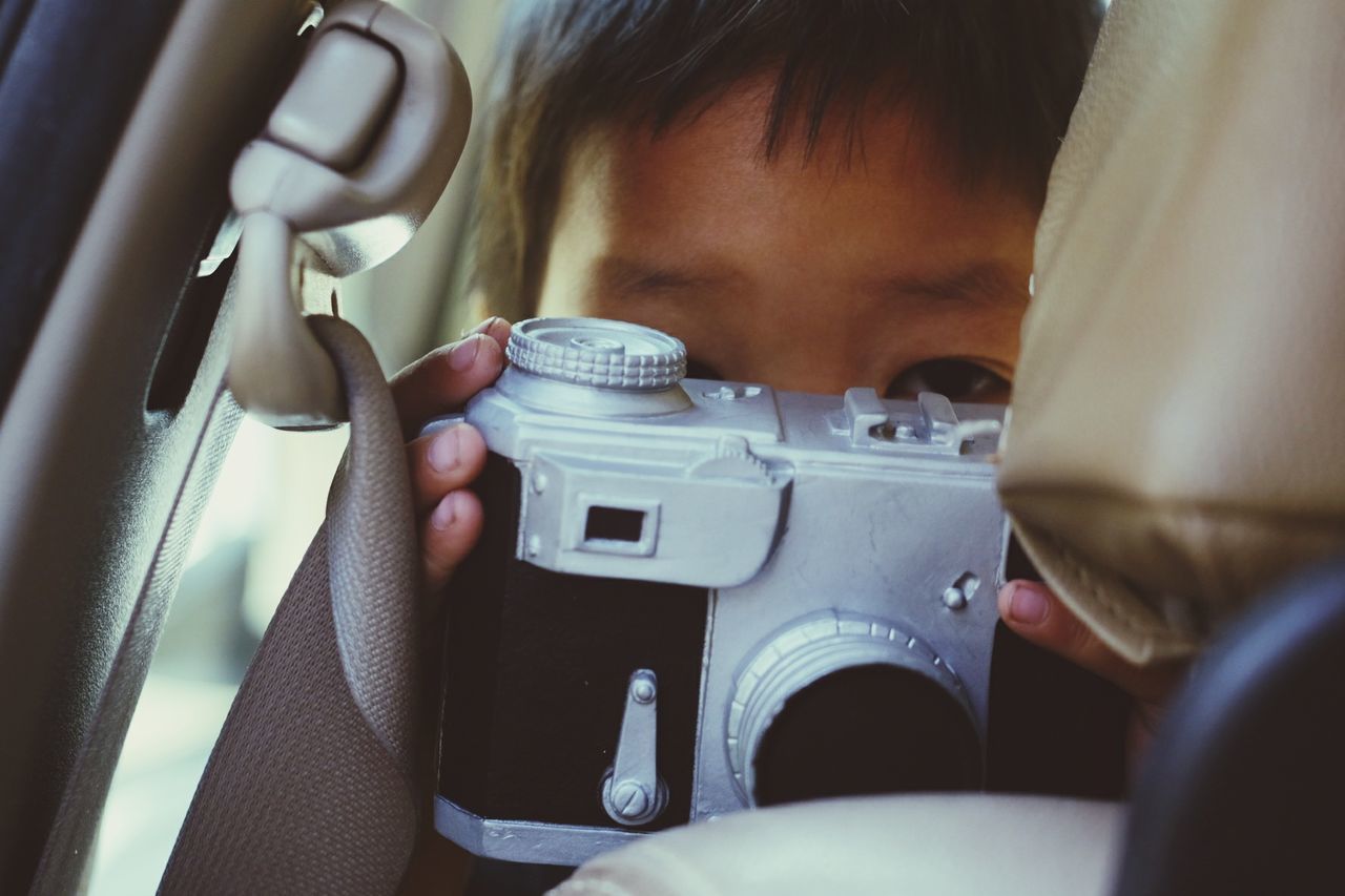 Close-up portrait of boy photographing in car