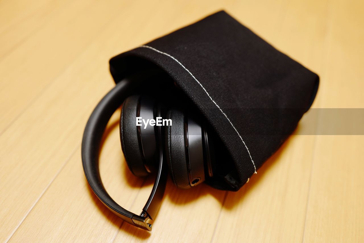 Close-up of headphones with pouch on wooden table