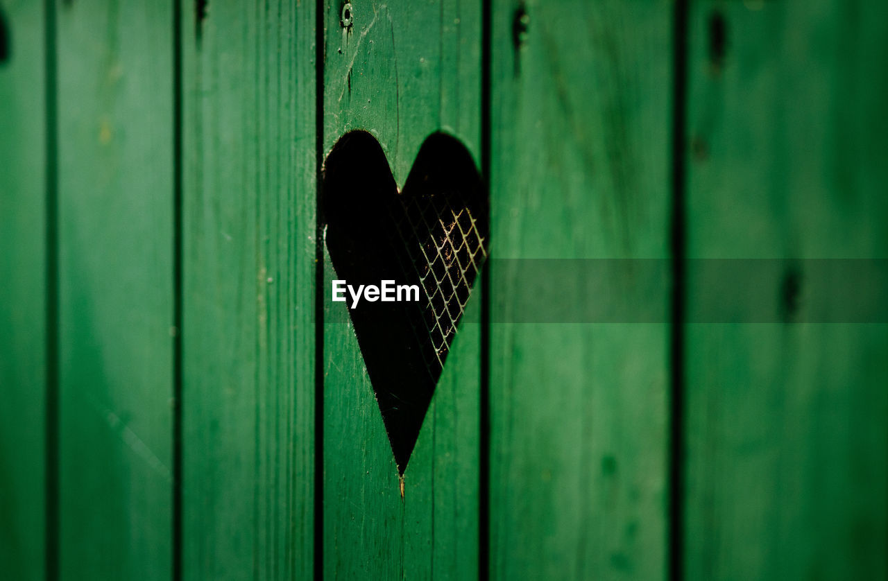 Heart shape window on green wooden door