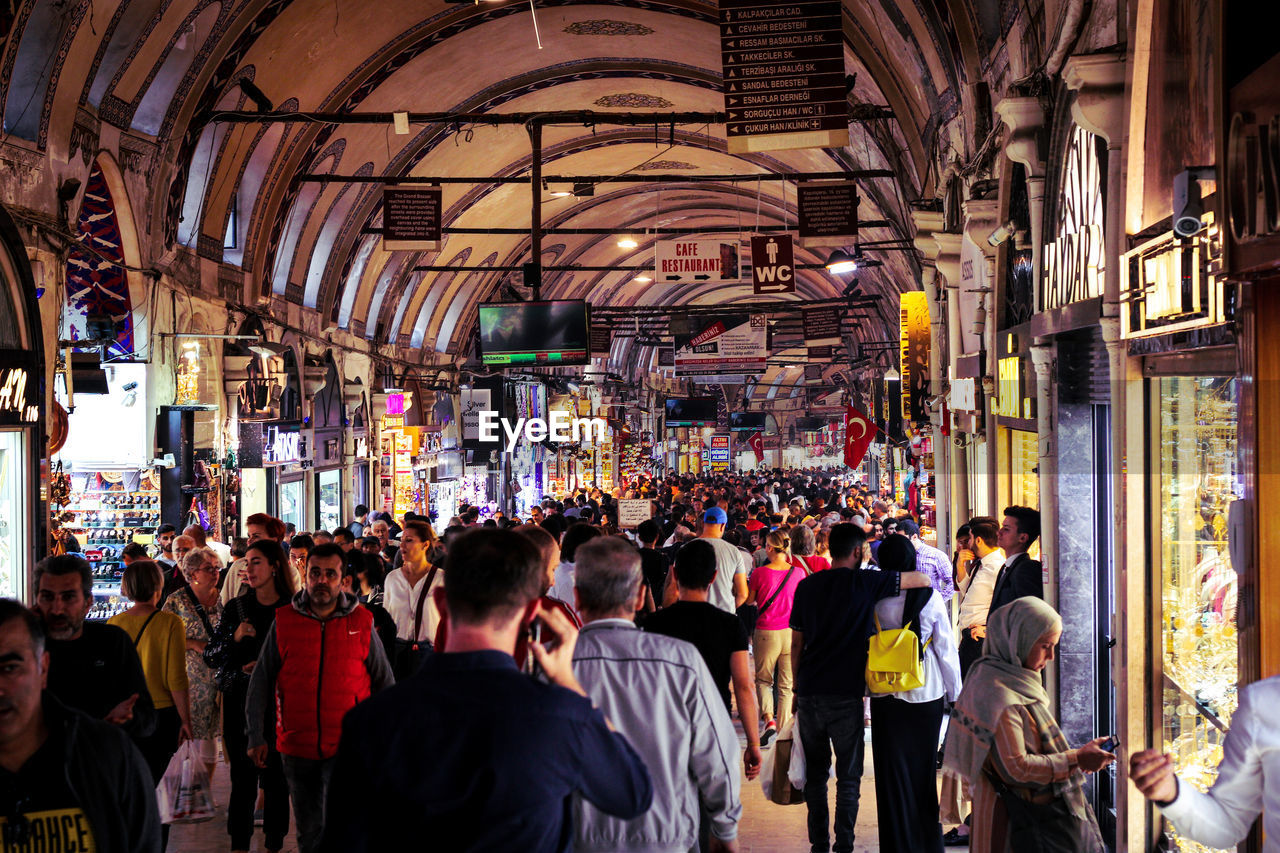 PEOPLE WALKING ON ILLUMINATED STREET AT NIGHT