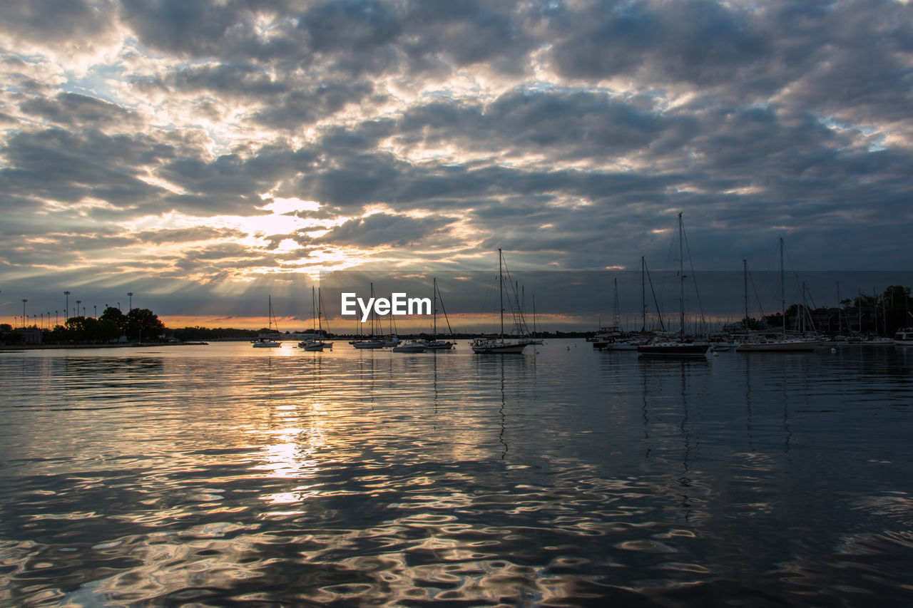 SAILBOATS IN SEA AT SUNSET