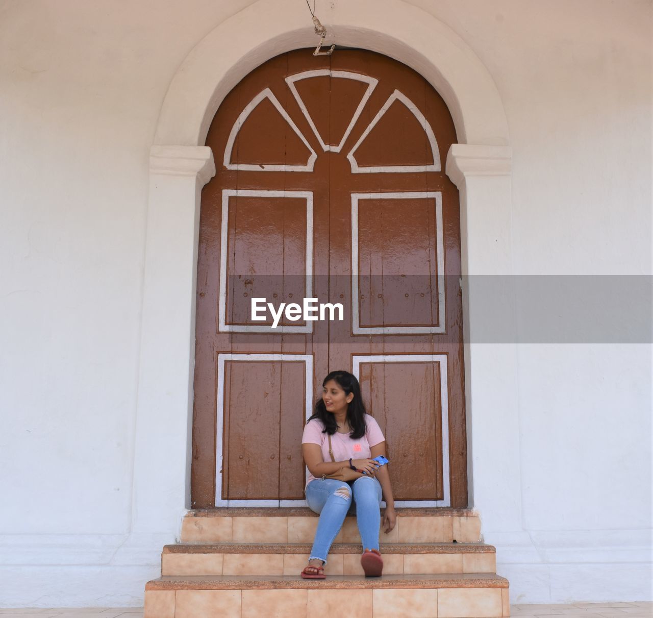 Full length of woman sitting at entrance of building