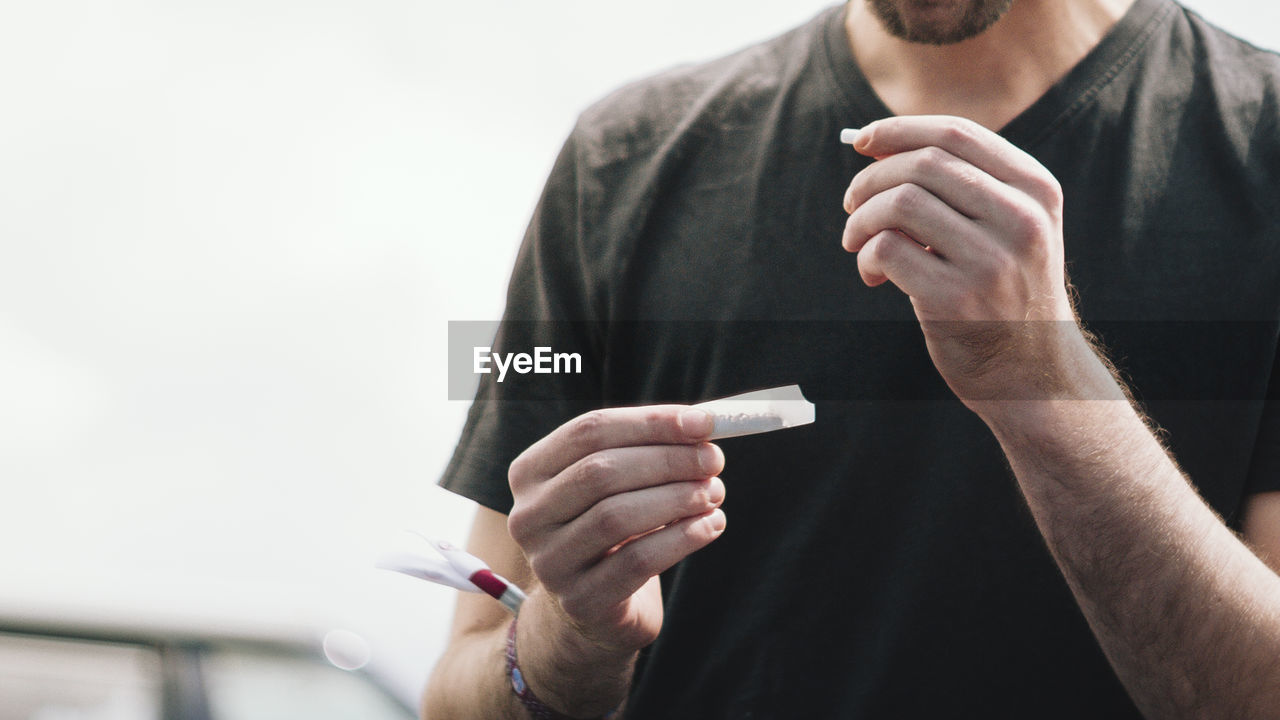 Midsection of man making marijuana joint