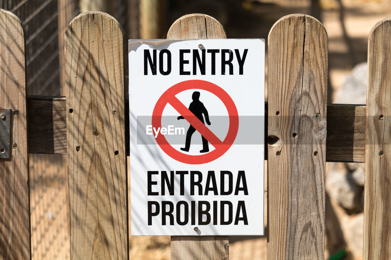 Close-up of warning sign on wooden fence