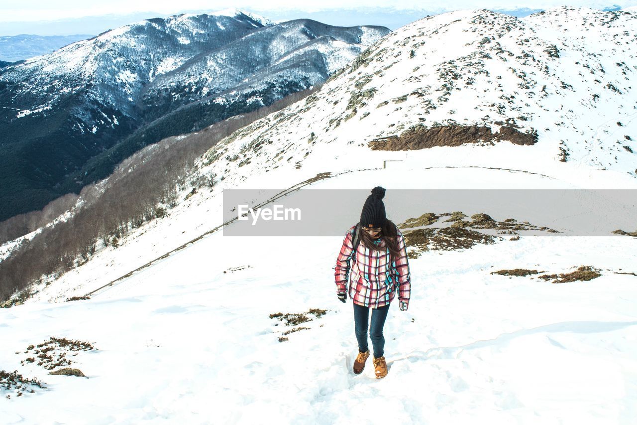 REAR VIEW OF WOMAN ON SNOWCAPPED MOUNTAIN