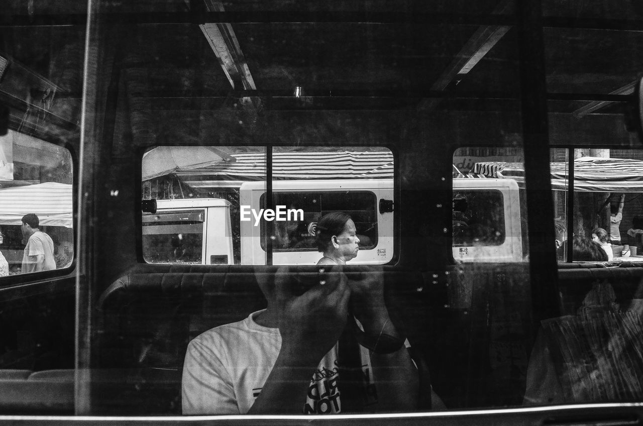 Reflection of woman photographing in bus