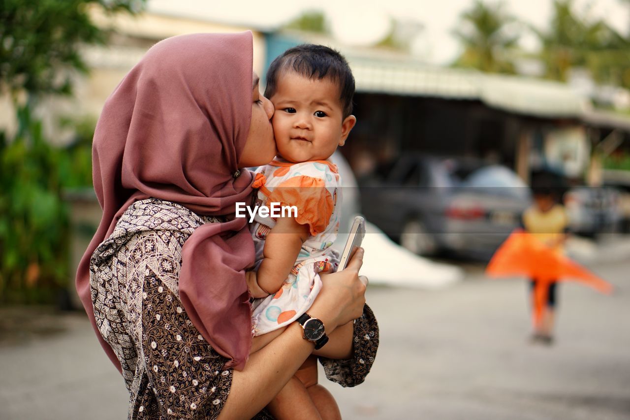 Close-up of mother kissing daughter on road