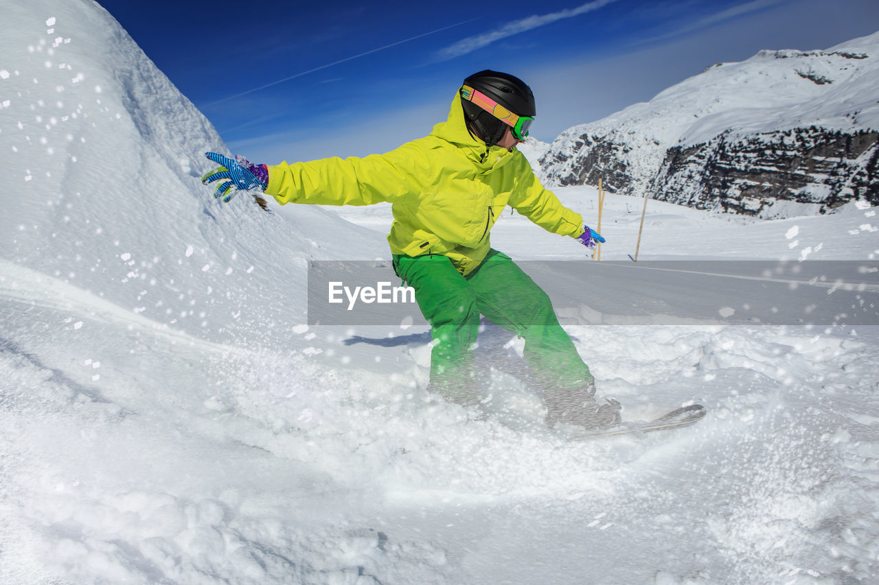 Full length of man snowboarding on snowcapped mountain
