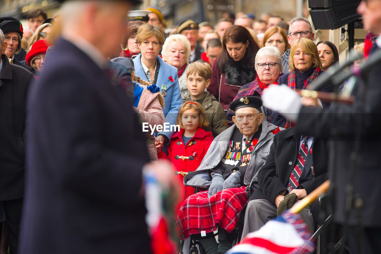 REAR VIEW OF PEOPLE SITTING IN A CROWD