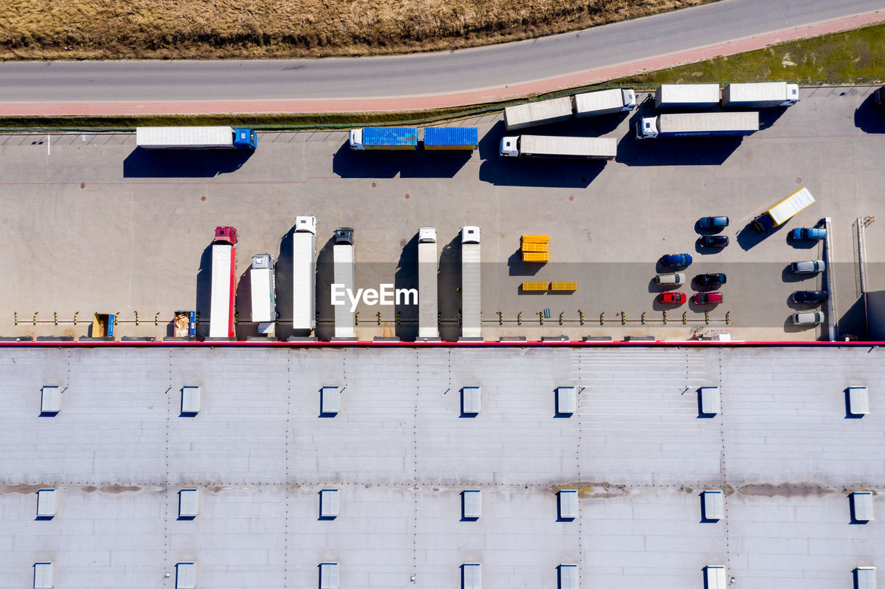 Aerial shot of truck with attached semi trailer leaving industrial warehouse/ storage 