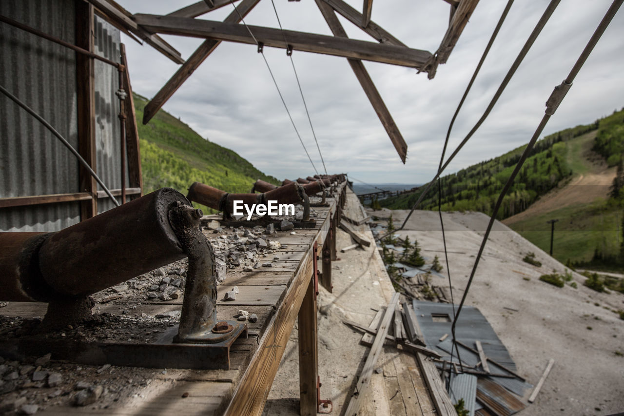 Abandoned metallic structure by mountain against sky