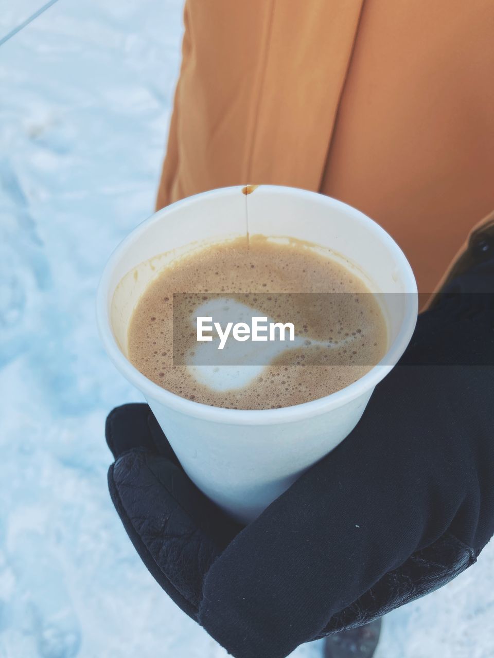 CLOSE-UP OF HAND HOLDING COFFEE CUP WITH SPOON